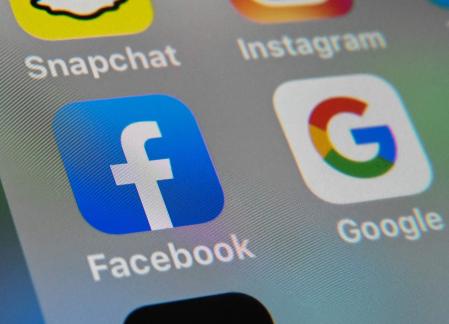 (FILES) This file photo taken on October 1, 2019, shows the logos of mobile apps Facebook and Google displayed on a tablet in Lille, France. - Dozens of US states joined forces in a lawsuit filed on July 7, 2021 accusing Google of abusing its power when it comes to getting apps for Android-powered mobile devices. The litigation aimed at the Play Store online shop for apps and other digital content for Android smartphones comes as the power of Big Tech firms is facing increasing pressure from regulators and lawsuits. (Photo by DENIS CHARLET / AFP)